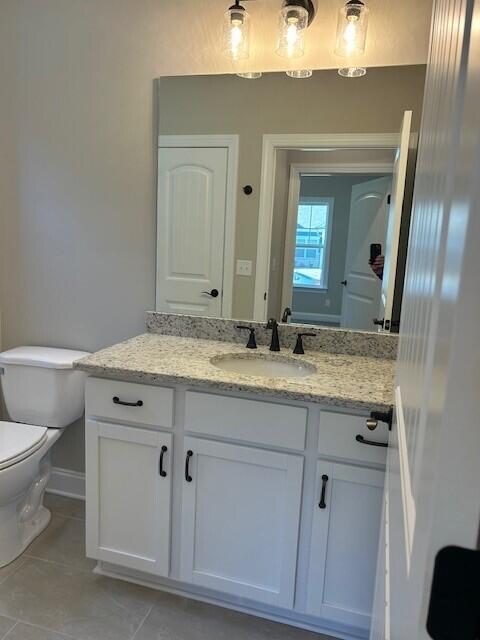 bathroom featuring toilet, vanity, and tile patterned flooring