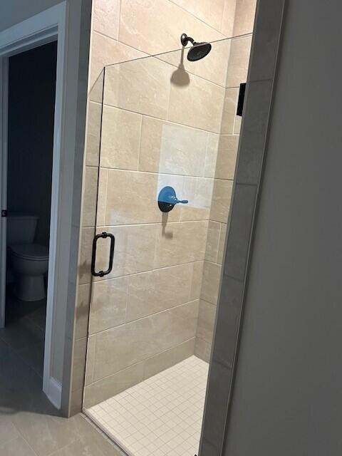 bathroom with toilet, tile patterned floors, and a shower with door