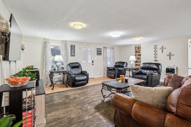 living room featuring heating unit, dark hardwood / wood-style floors, and a textured ceiling