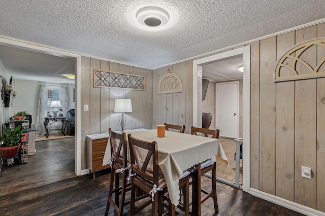 dining area with a textured ceiling, dark hardwood / wood-style flooring, and wooden walls