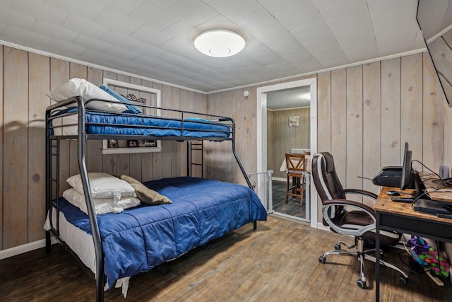 bedroom with wood walls, dark hardwood / wood-style floors, and ornamental molding