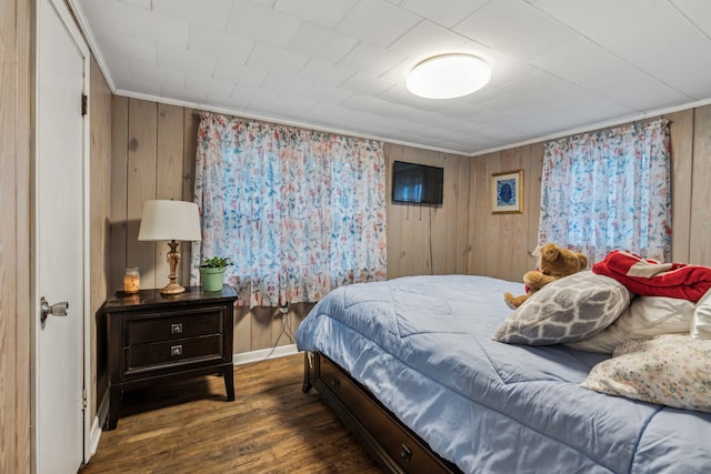 bedroom with ornamental molding, dark hardwood / wood-style floors, and wooden walls