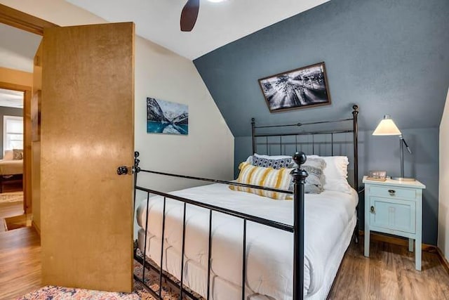 bedroom with ceiling fan, vaulted ceiling, and hardwood / wood-style floors