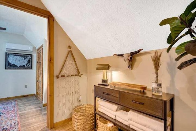 interior details featuring hardwood / wood-style flooring, a wall mounted AC, and a textured ceiling