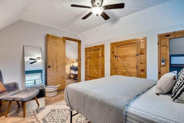 bedroom featuring vaulted ceiling, hardwood / wood-style floors, a textured ceiling, and ceiling fan