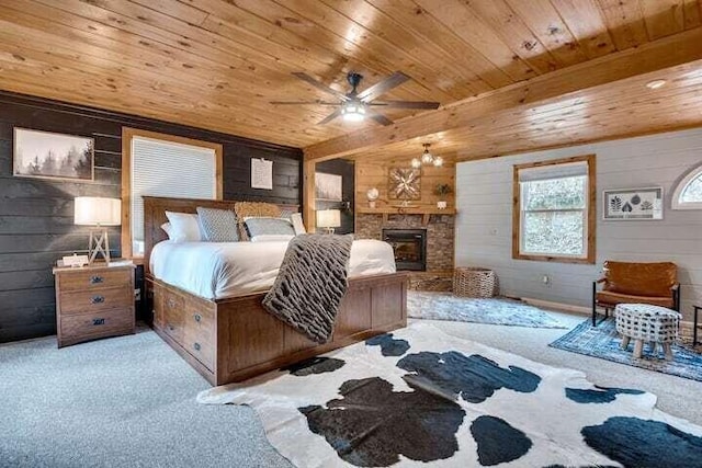 bedroom with ceiling fan, light colored carpet, a fireplace, and wooden walls