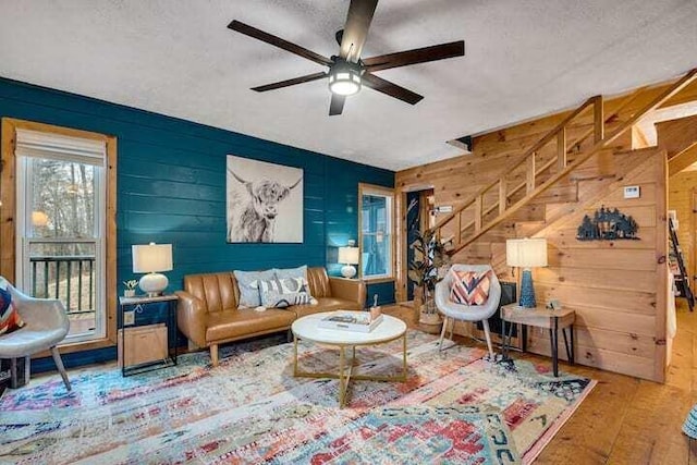 sitting room featuring ceiling fan, hardwood / wood-style flooring, wooden walls, and a textured ceiling