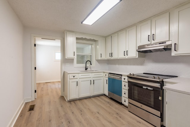 kitchen with a textured ceiling, white cabinets, stainless steel appliances, sink, and light hardwood / wood-style flooring