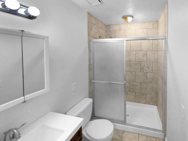 bathroom featuring toilet, a shower with shower door, tile patterned floors, and vanity