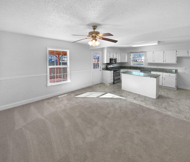 kitchen with stainless steel electric stove, ceiling fan, white cabinets, light colored carpet, and a center island