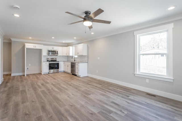 unfurnished living room with ceiling fan, sink, ornamental molding, and light hardwood / wood-style floors