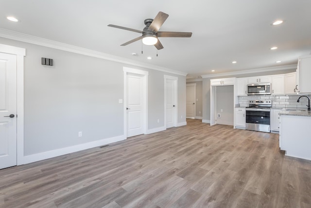 unfurnished living room featuring ornamental molding, light hardwood / wood-style floors, and sink