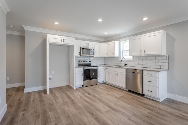 kitchen with tasteful backsplash, sink, crown molding, stainless steel appliances, and white cabinets