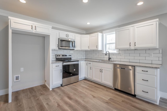 kitchen with white cabinetry, appliances with stainless steel finishes, light stone countertops, light hardwood / wood-style flooring, and sink