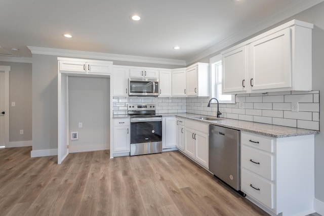 kitchen featuring stainless steel appliances, tasteful backsplash, white cabinets, light stone counters, and sink