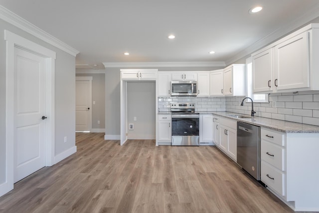 kitchen with appliances with stainless steel finishes, tasteful backsplash, white cabinets, light stone counters, and sink