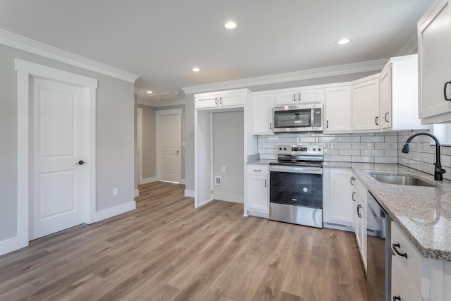 kitchen featuring white cabinets, stainless steel appliances, sink, backsplash, and light stone counters