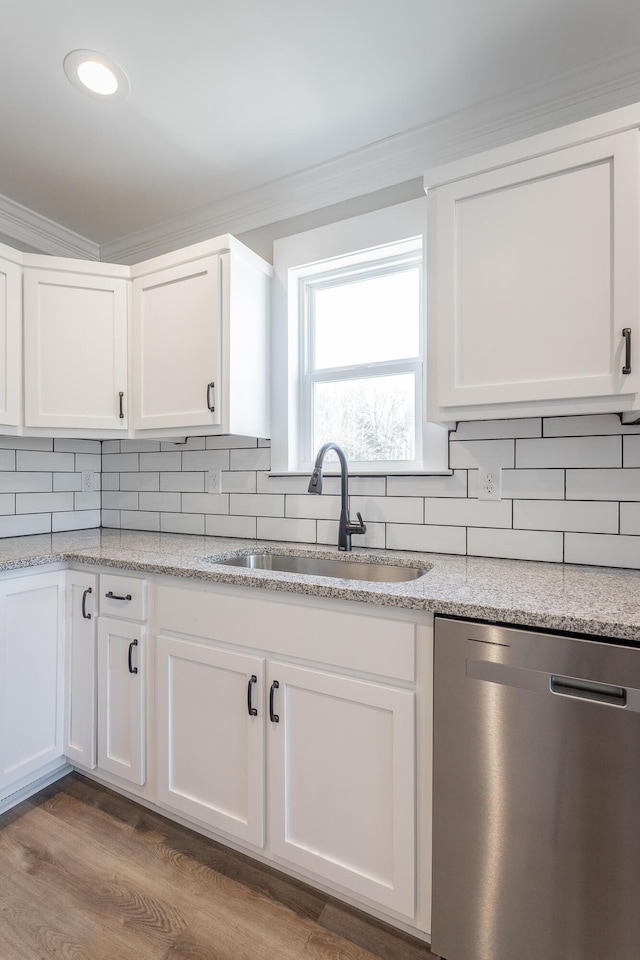 kitchen featuring stainless steel dishwasher, white cabinets, decorative backsplash, and sink