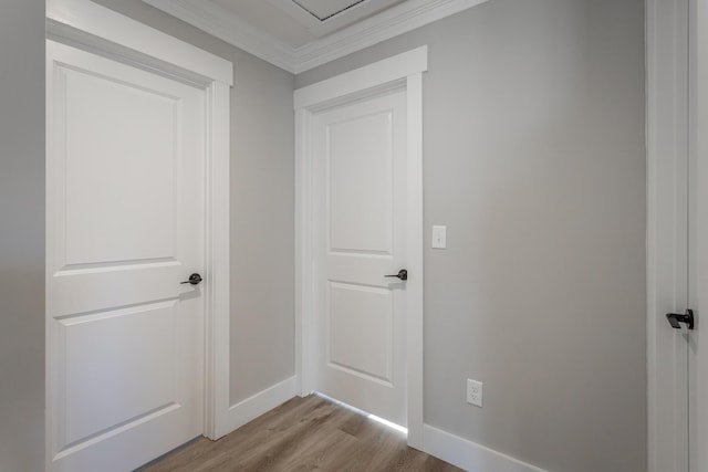 corridor with light wood-type flooring and crown molding