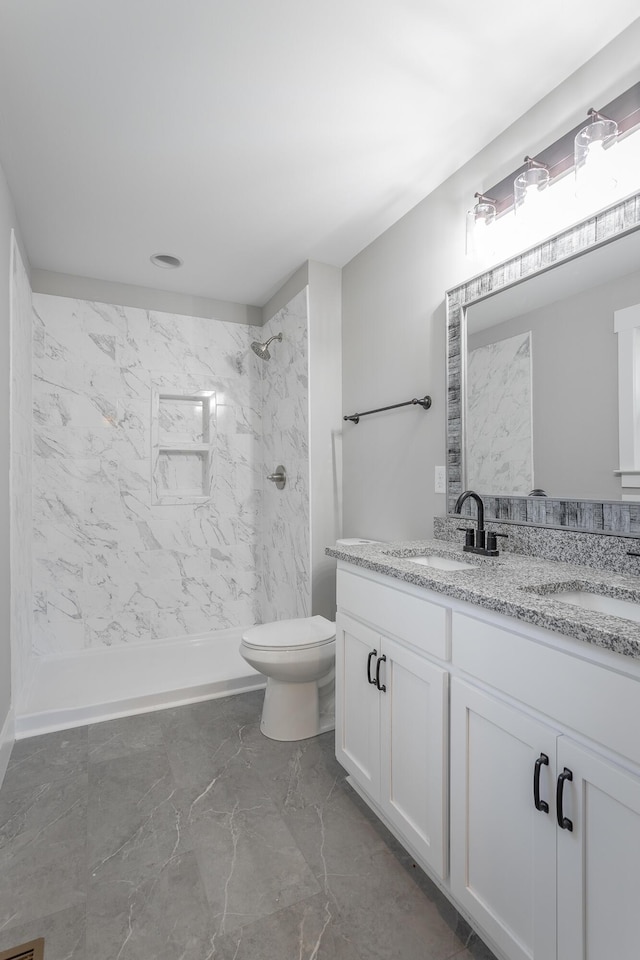 bathroom featuring toilet, vanity, and tiled shower