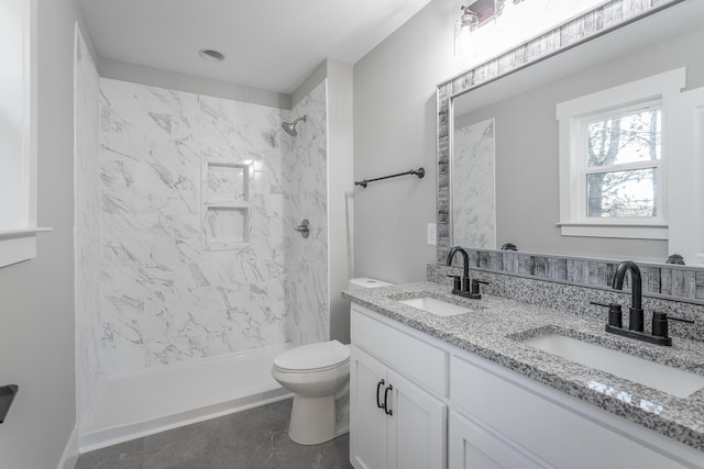 bathroom featuring toilet, vanity, and a tile shower