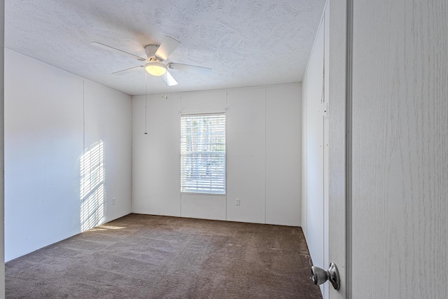 empty room with ceiling fan, a textured ceiling, and dark carpet