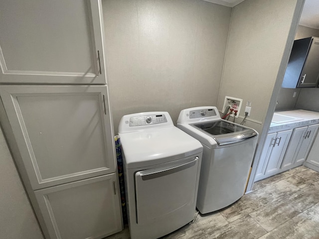 washroom featuring washer and clothes dryer, light hardwood / wood-style floors, and cabinets