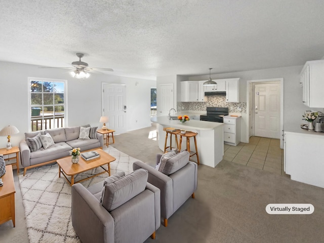 living room featuring sink, ceiling fan, light colored carpet, and a textured ceiling