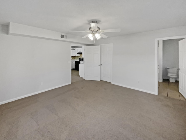 unfurnished bedroom featuring ceiling fan, light carpet, and ensuite bathroom