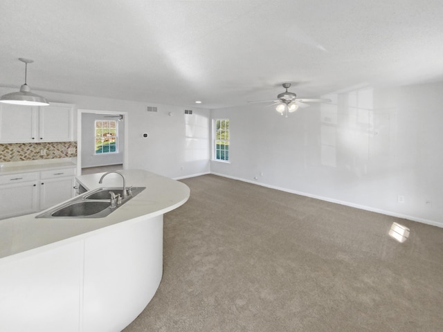 kitchen with decorative light fixtures, sink, backsplash, white cabinetry, and carpet