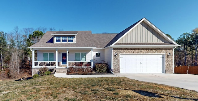 craftsman-style house featuring covered porch, a front yard, and a garage