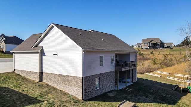 view of property exterior with a balcony and a lawn