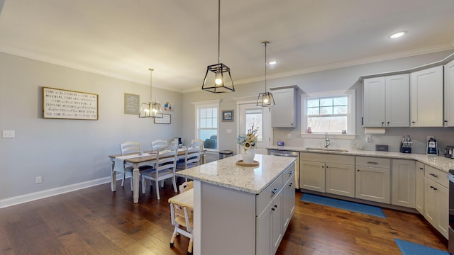 kitchen with a kitchen island, dark hardwood / wood-style flooring, sink, hanging light fixtures, and light stone counters