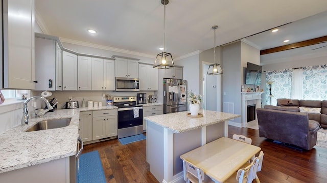 kitchen with light stone countertops, a center island, decorative light fixtures, stainless steel appliances, and sink