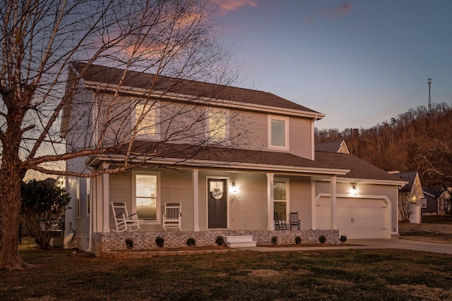 view of front of house with a garage, covered porch, and a yard