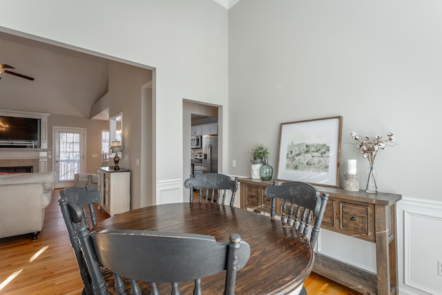 dining area featuring ceiling fan, a tile fireplace, and light hardwood / wood-style flooring