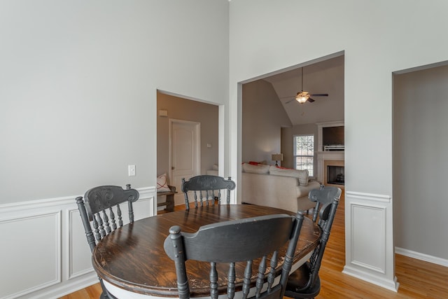 dining room with ceiling fan, light hardwood / wood-style flooring, and vaulted ceiling