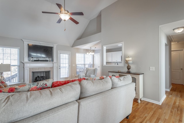 living room featuring light hardwood / wood-style floors, high vaulted ceiling, ceiling fan, and a fireplace