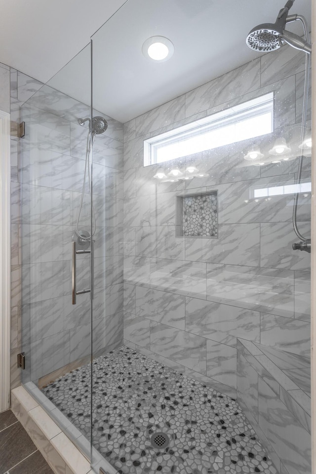 bathroom featuring a shower with shower door, tile patterned flooring, and a healthy amount of sunlight