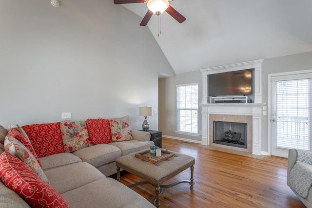 living room featuring light hardwood / wood-style floors, high vaulted ceiling, ceiling fan, and a fireplace