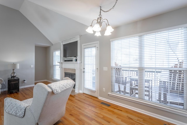 living room featuring vaulted ceiling, an inviting chandelier, and hardwood / wood-style flooring