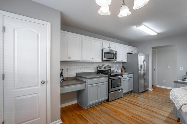 kitchen with decorative light fixtures, backsplash, white cabinetry, and appliances with stainless steel finishes