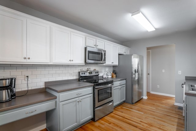 kitchen featuring white cabinets, backsplash, stainless steel appliances, and light hardwood / wood-style floors