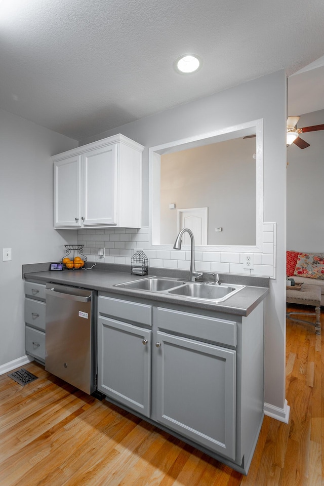 kitchen with white cabinets, dishwasher, tasteful backsplash, sink, and light wood-type flooring