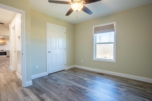 unfurnished bedroom with ceiling fan, visible vents, baseboards, and wood finished floors