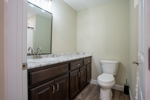 bathroom featuring toilet, vanity, baseboards, and wood finished floors