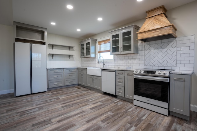 kitchen featuring dishwashing machine, premium range hood, electric range, gray cabinets, and a sink