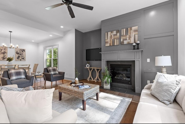 living room with ceiling fan with notable chandelier and dark hardwood / wood-style flooring