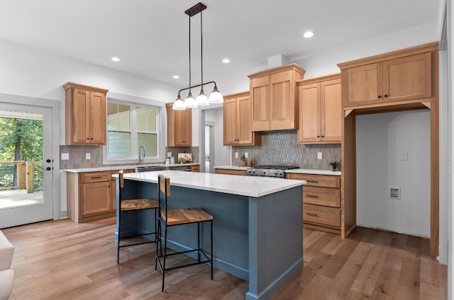 kitchen featuring decorative light fixtures, light hardwood / wood-style flooring, stainless steel stove, and a center island