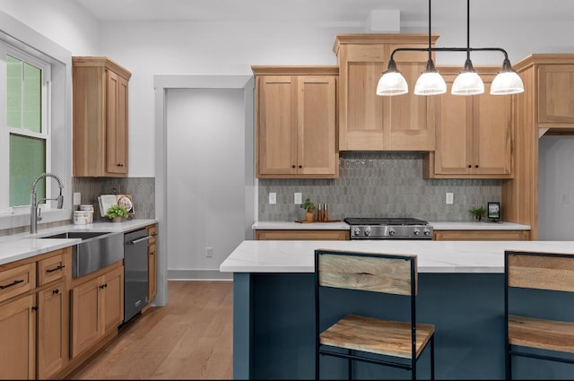 kitchen featuring appliances with stainless steel finishes, light wood-type flooring, a kitchen breakfast bar, pendant lighting, and sink